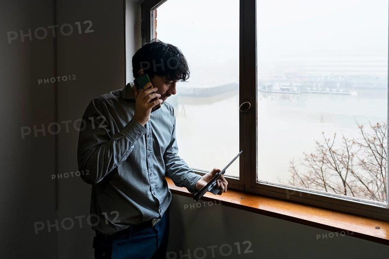 Latino businessman working in an office overlooking the river. Talking on the phone and reviewing notes
