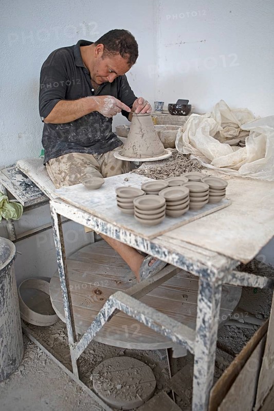 Moroccan potter at work: turning at the potter's pane and shaping ceramic vessels and pottery: Jugs