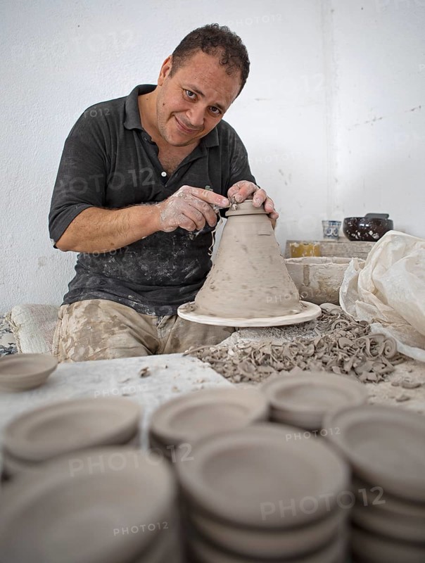 Moroccan potter at work: turning at the potter's pane and shaping ceramic vessels and pottery: Jugs