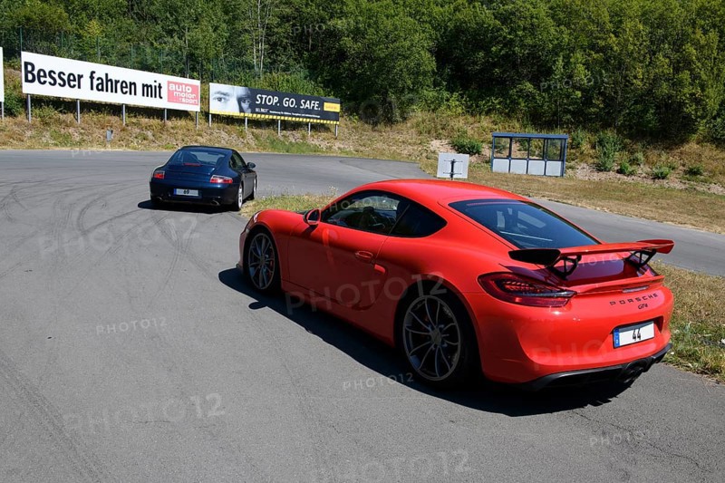 Two sports cars in front red Porsche Cayman GT4 with rear spoiler in the background Porsche 911 996 Carrera on course of driving safety training