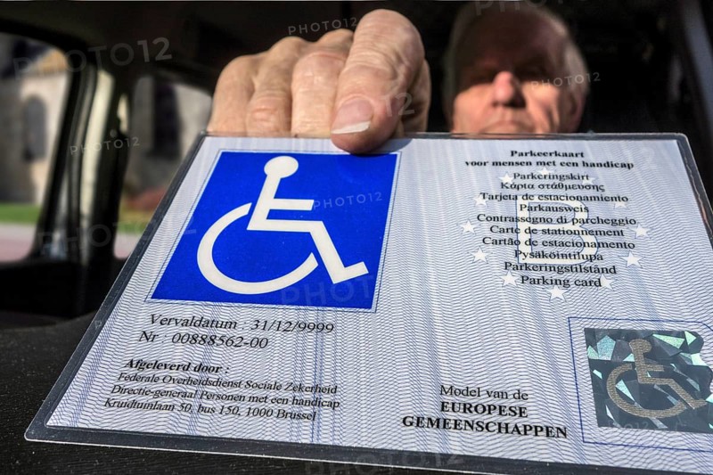 Disabled elderly man puts EU parking card for people with disabilities