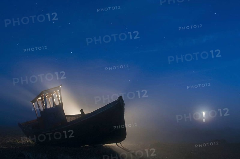 Abandoned fishing boat on a shingle beach at night