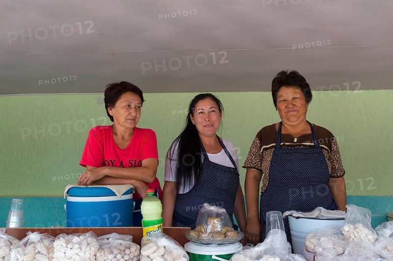 Group of Kazakh woman behind their stand with goat cheese and kumis