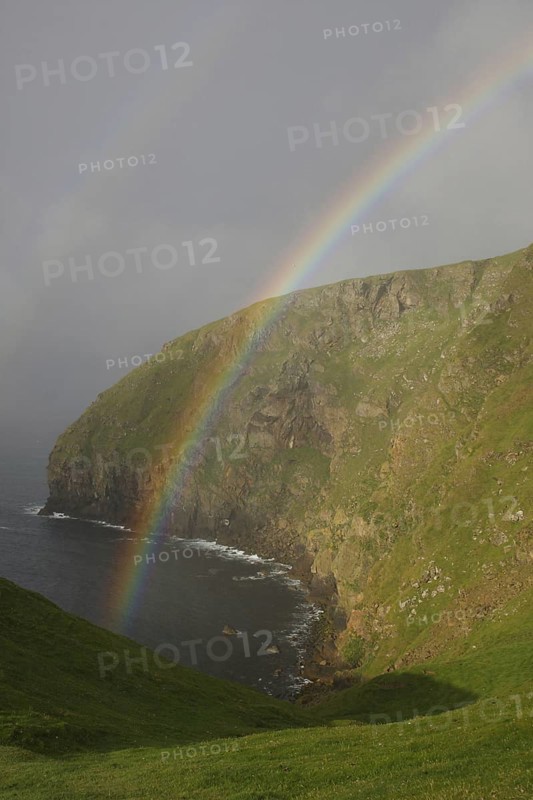 View of double rainbow over coastal cliff habitat