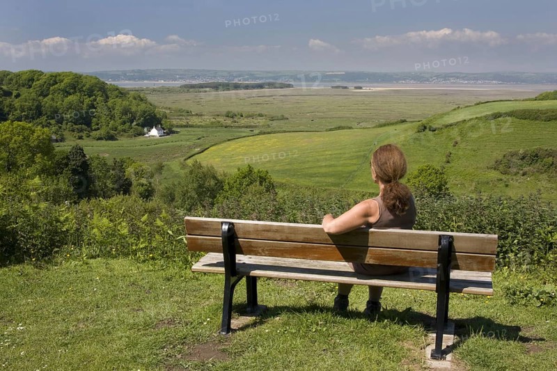Woman sitting on bench overlooking the coast