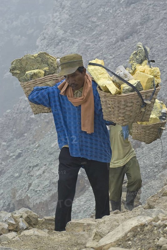Local men carry sulphur blocks in baskets on the slopes of the volcanic crater