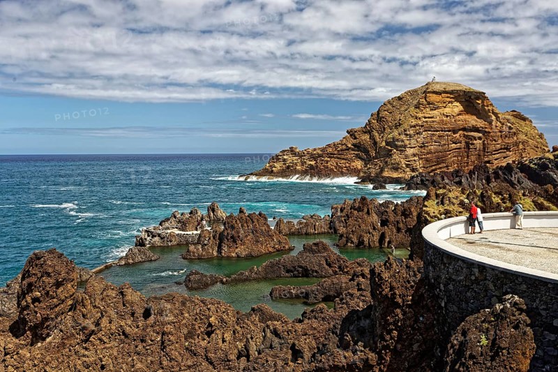 Tourists look from viewing platform at natural lava pools for bathing
