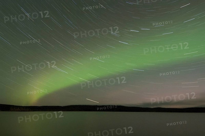 Aurora Borealis and star trails over the lake at night