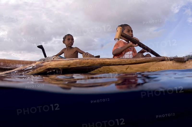Boys rowing a canoe at sea