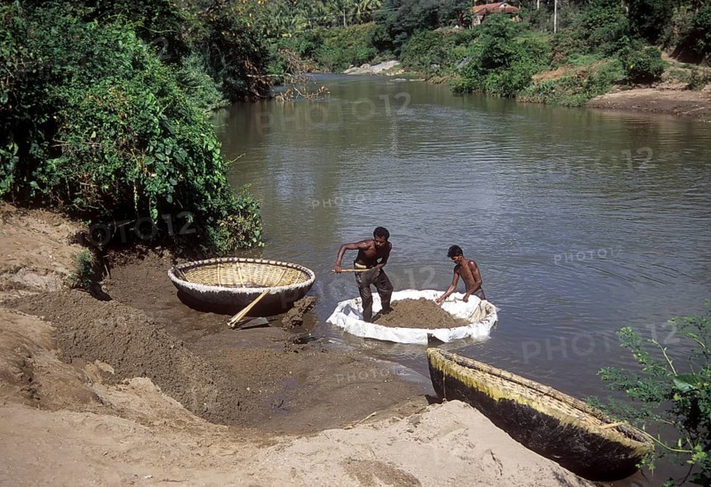 Collecting sand from river on coracle or parisal in Tamil Nadu