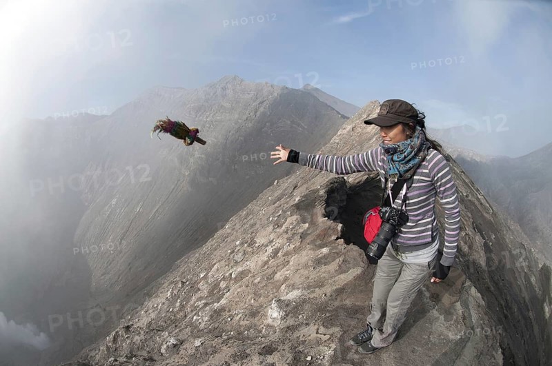Tourist throwing offering into smoke vent of volcano