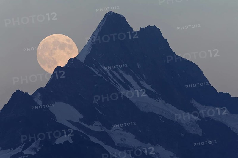 Full Moon rising over mountain peak at dusk