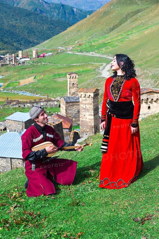 Georgian people from the folklore group playing panduri and dancing in traditional Georgian dress