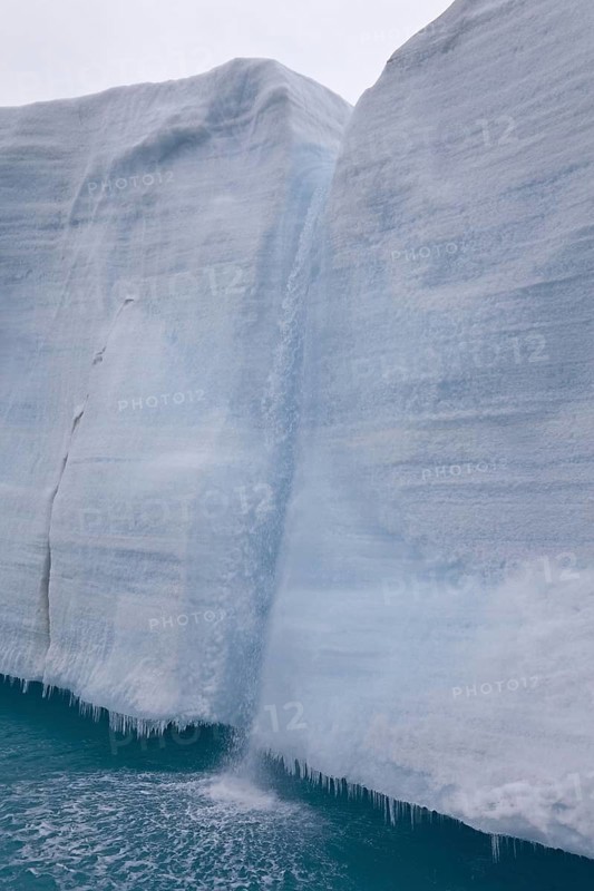 Coastal glacier terminus with waterfall from melting ice