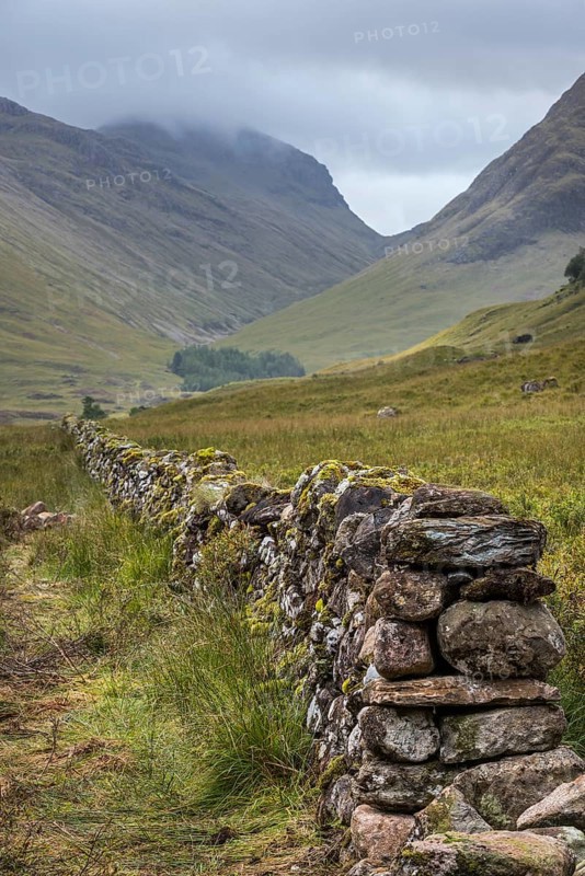Old dry stone wall in moorland leading to the mountain Bidean nam Bian and the famous Three Sisters of Glen Coe