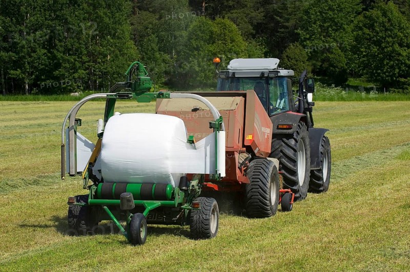 Tractor-drawn baler and mechanical bale wrapper with plastic-wrapped silage round bales