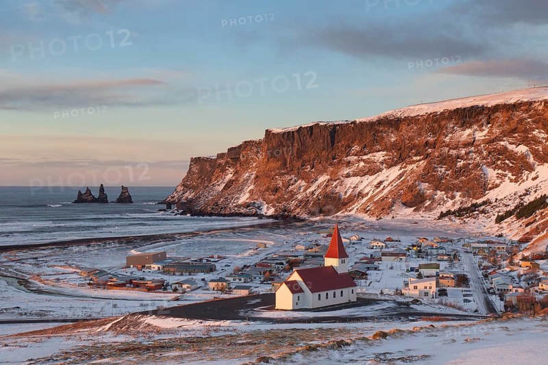 Reynisdrangar sea stack and Vik church in Vik i Myrdal village in winter
