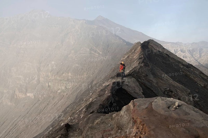 Tourists standing on edge of volcanic crater