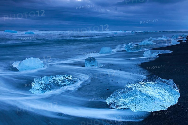 Melting ice blocks washing up on the beach along the Atlantic coast at Breidamerkursandur black sands in winter