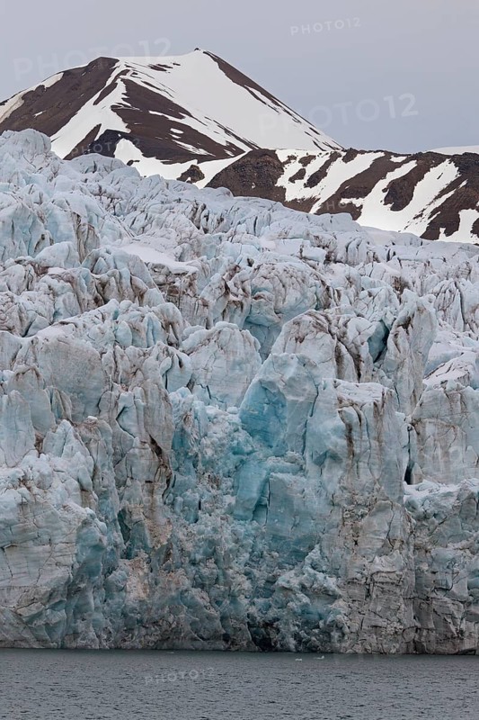 Crumbling ice wall of Nordenskioeldbreen glacier ending in Adolfsbukta