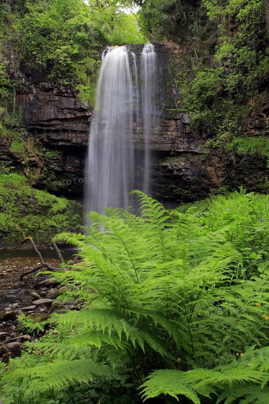 Waterfall flowing over a defaced edge of hard sandstone