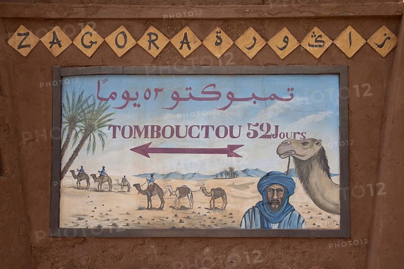 Signpost 'Tombouctou 52 days' in desert town