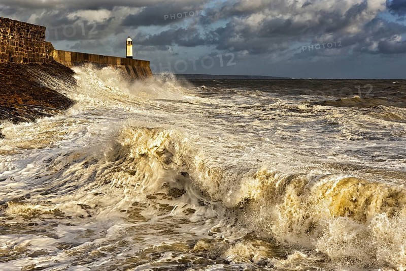 Wave-bombed seafront and coastal town lighthouse