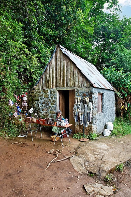 Woman sitting in front of stone house