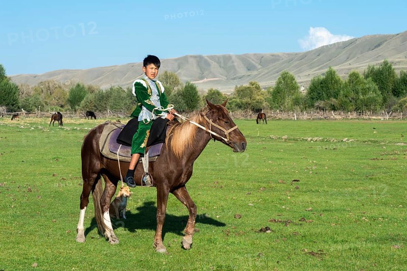 Kazakh boy in traditional dress on a horse