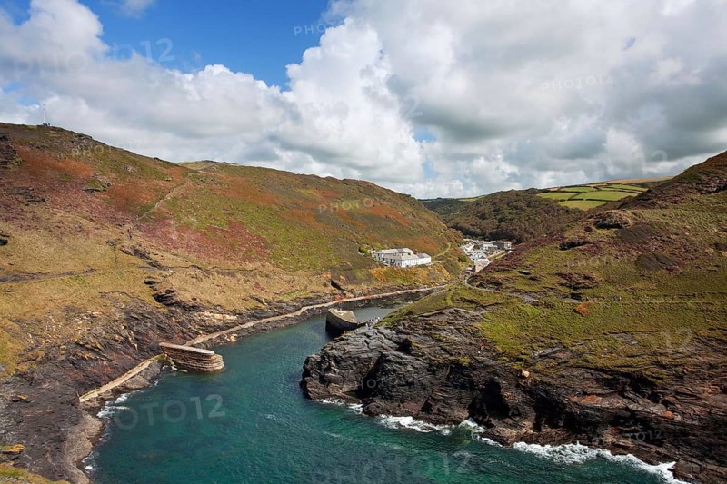 View of the coastline with breakwater and the old quay in the foreground leading to the village in the valley