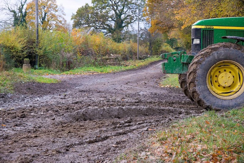 John Deere tractor beside muddy country road