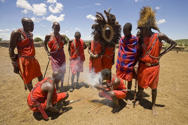 Maasai tribesmen light fire at the edge of the village