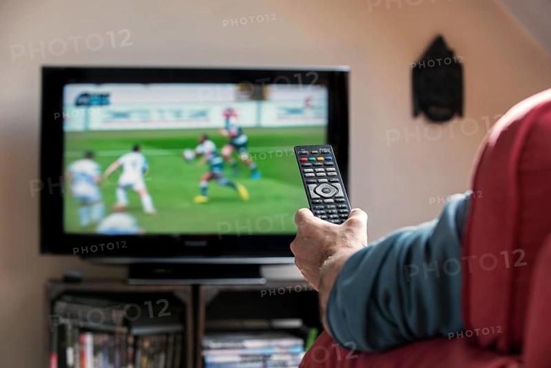 Man with remote control in front of TV