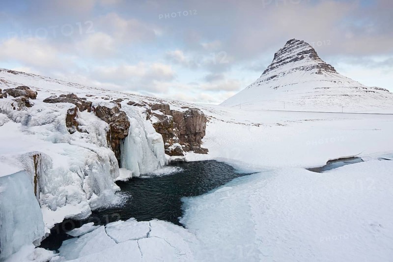 Kirkjufell mountain and the frozen waterfall Kirkjufellsfoss on Snaefellsnes peninsula in the snow in winter