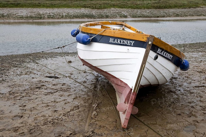 Boat moored on mud at edge of coastal stream
