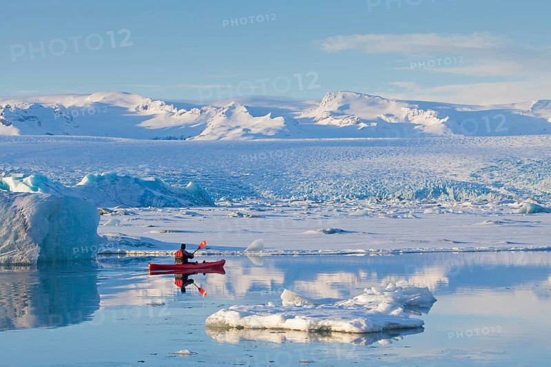 Kayaker in a red kayak on the glacier lagoon Joekulsarlon in winter