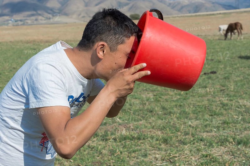 Kazakh man drinking fresh mare's milk from a bucket