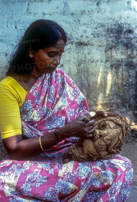 A woman carving on the shell of coconut