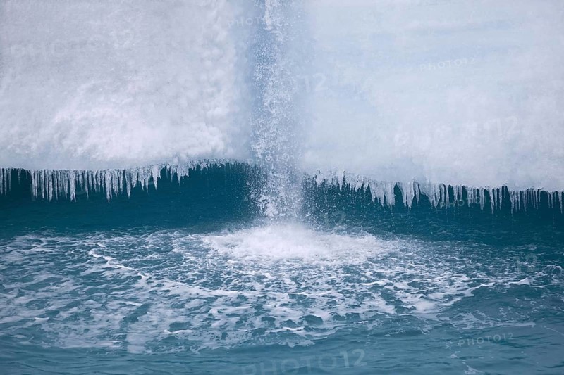 Coastal glacier terminus with waterfall from melting ice