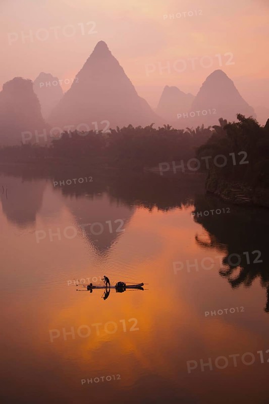 Traditional fisherman standing on a bamboo raft at sunrise