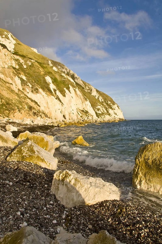 Coastal headland with small waves breaking on shingle and rocky beach