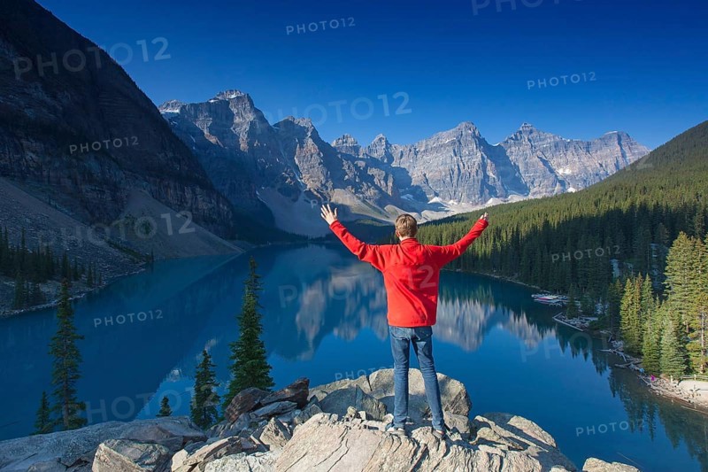 Tourist with open arms at the viewpoint overlooking Moraine Lake in the Valley of the Ten Peaks