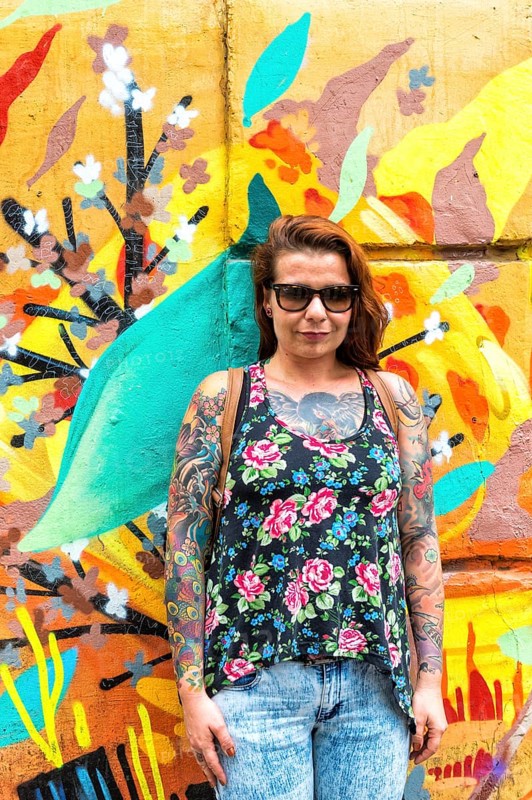 Tattooed woman in front of a wall covered with graffiti