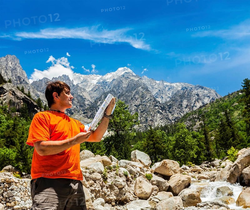 Hiker trekker studying map route on trek in Himalayas mountains. Himachal Pradesh