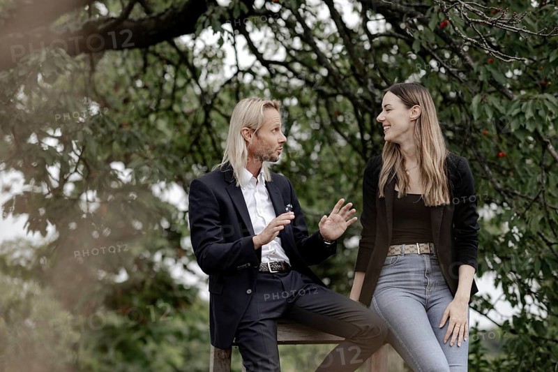 Man and woman talking on a wooden table in nature