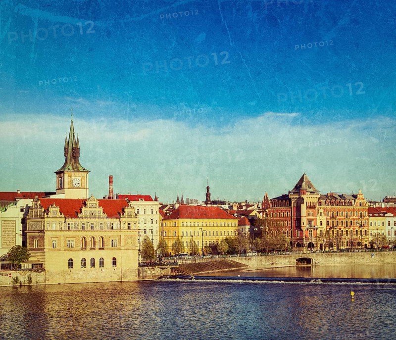 Vintage retro hipster style travel image of Prague Stare Mesto embankment view from Charles bridge on sunset with grunge texture overlaid. Prague