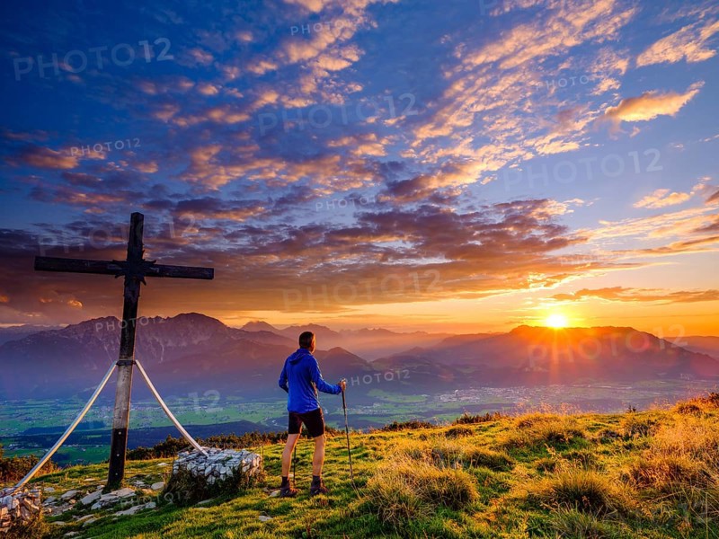 Mountaineers at the Schlenken summit cross at sunset clouds