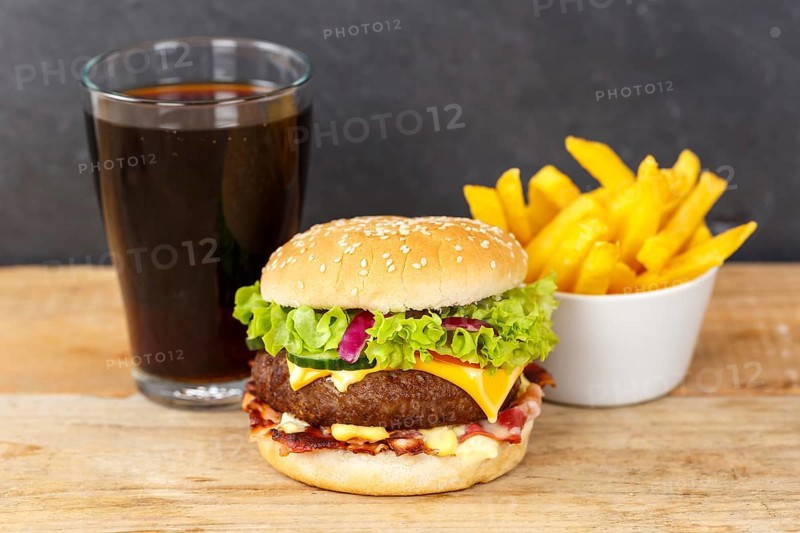 Hamburger cheeseburger fast food meal menu with fries and coke drink on wooden board in Stuttgart