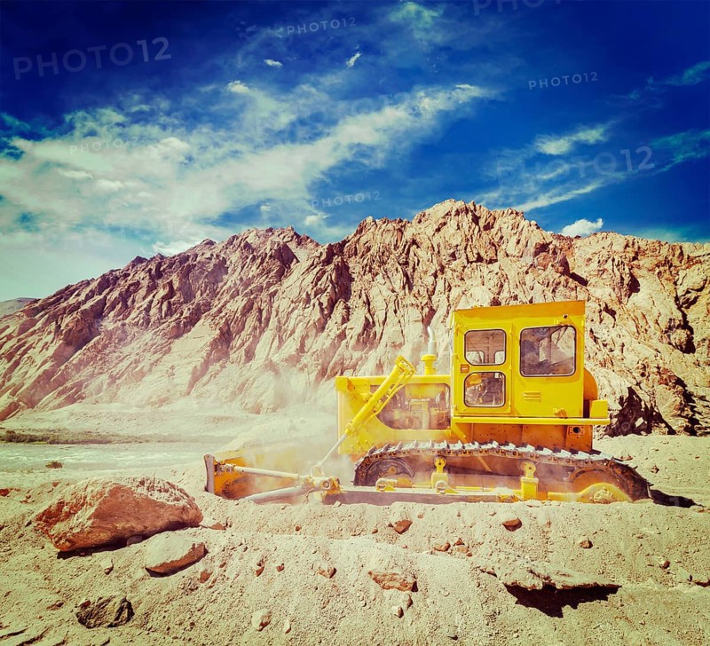 Vintage retro effect filtered hipster style travel image of Bulldozer doing road construction in Himalayas. Ladakh
