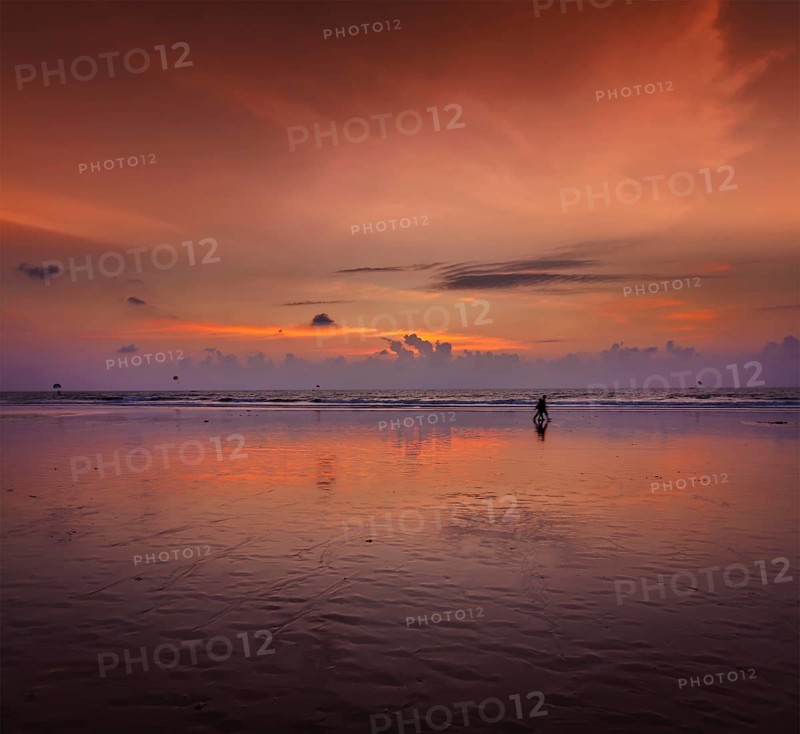 Couple walking on beach on romantic sunset. Baga beach. Goa